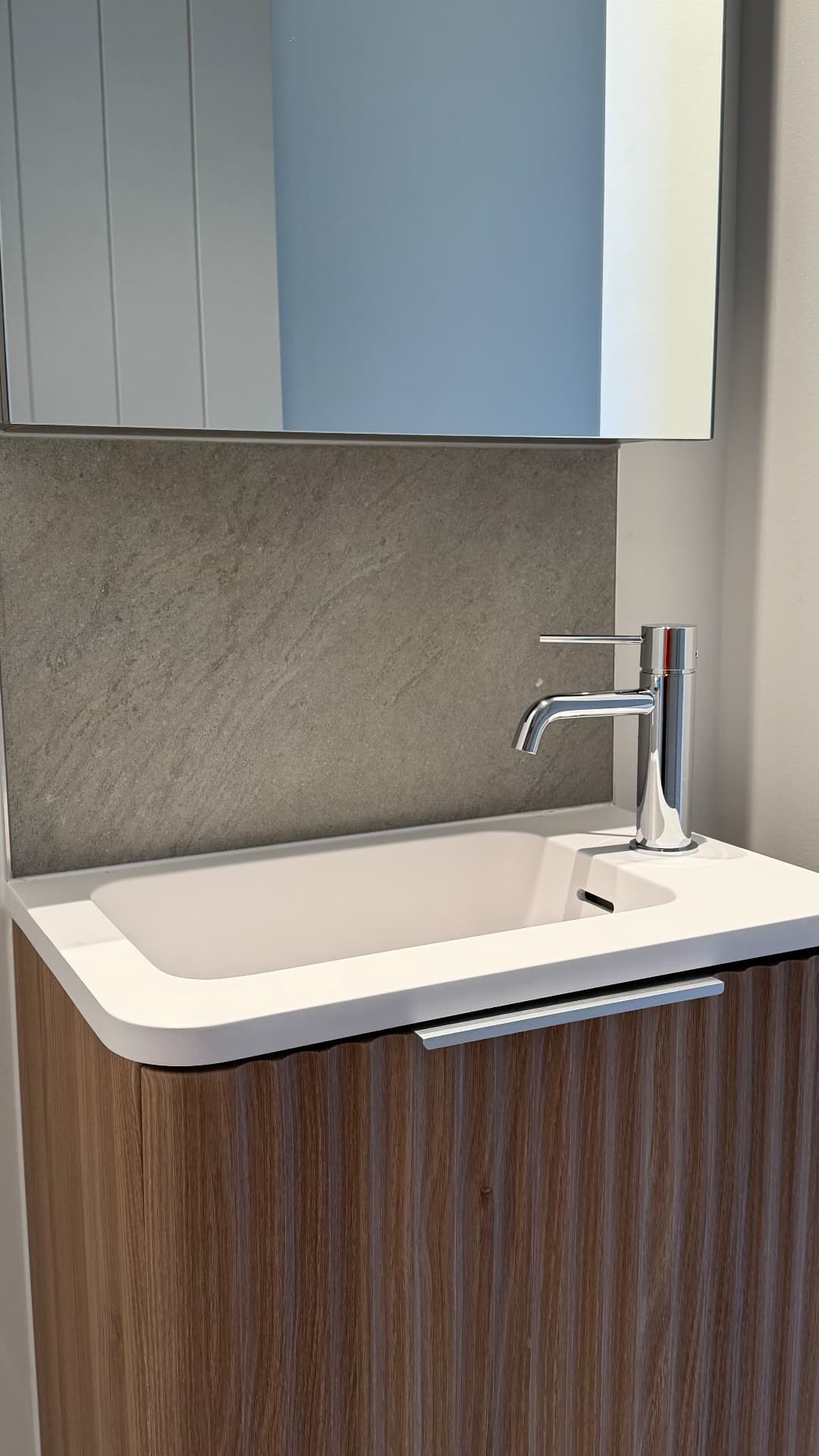 Powder room vanity with sealed basin and stone splashback