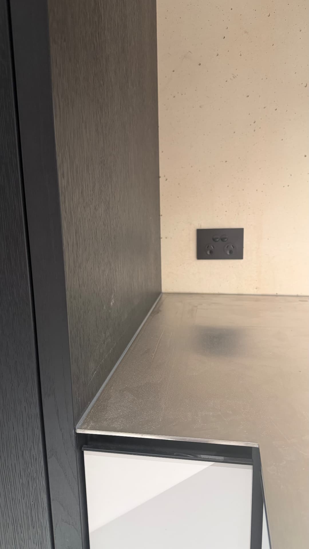 Sealed joint between stone benchtop, joinery and concrete wall