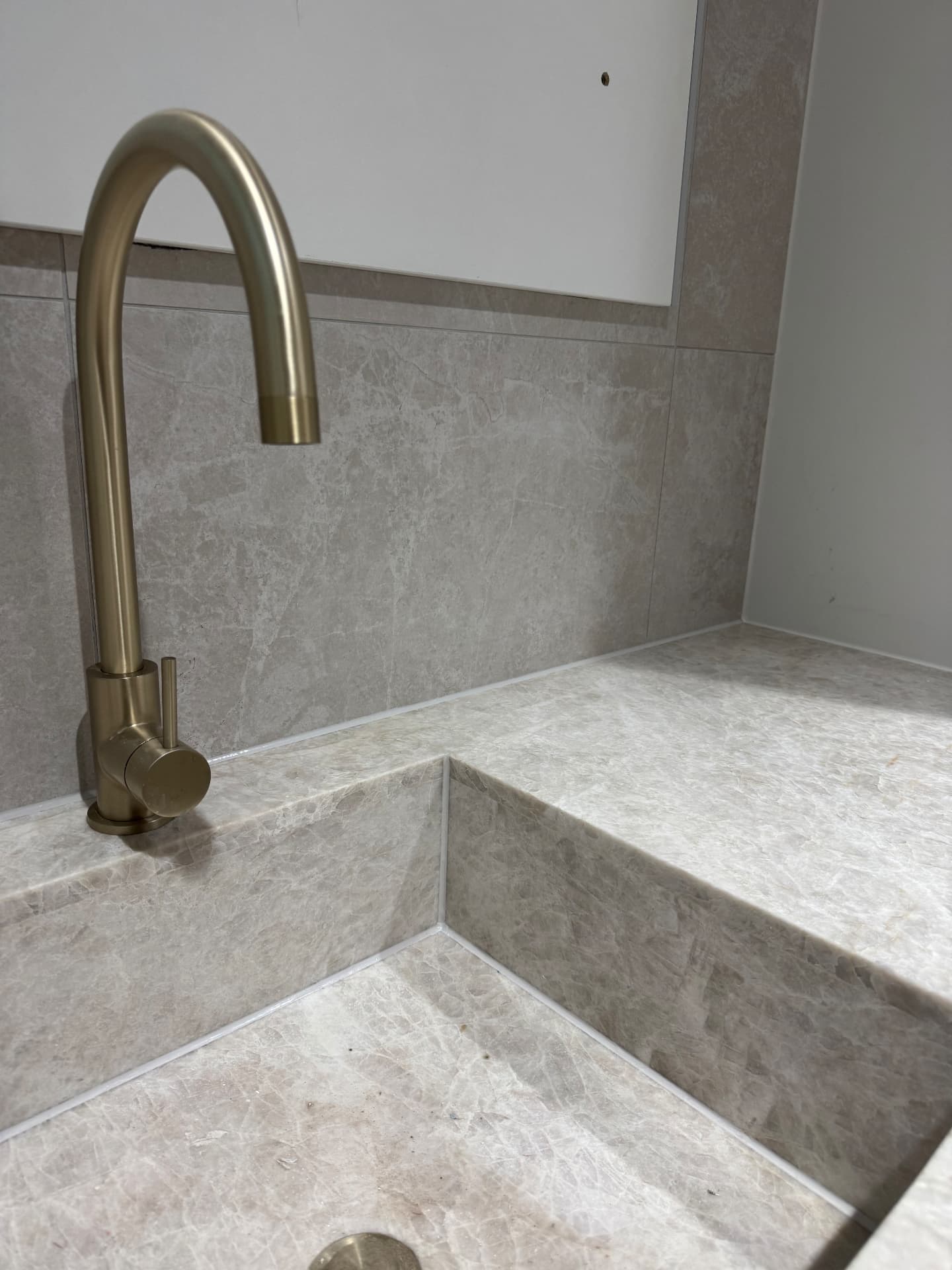 Sealed corner joints around tapware and stone benchtop shelf