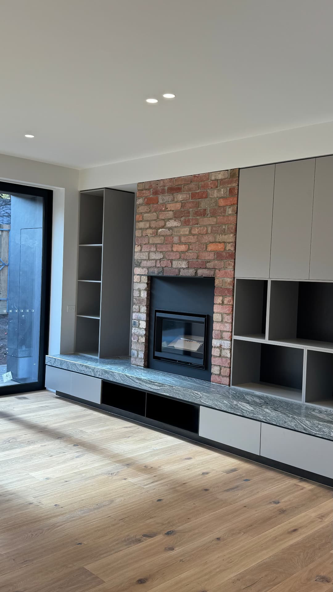 Living room joinery with sealed stone bench and brick fireplace