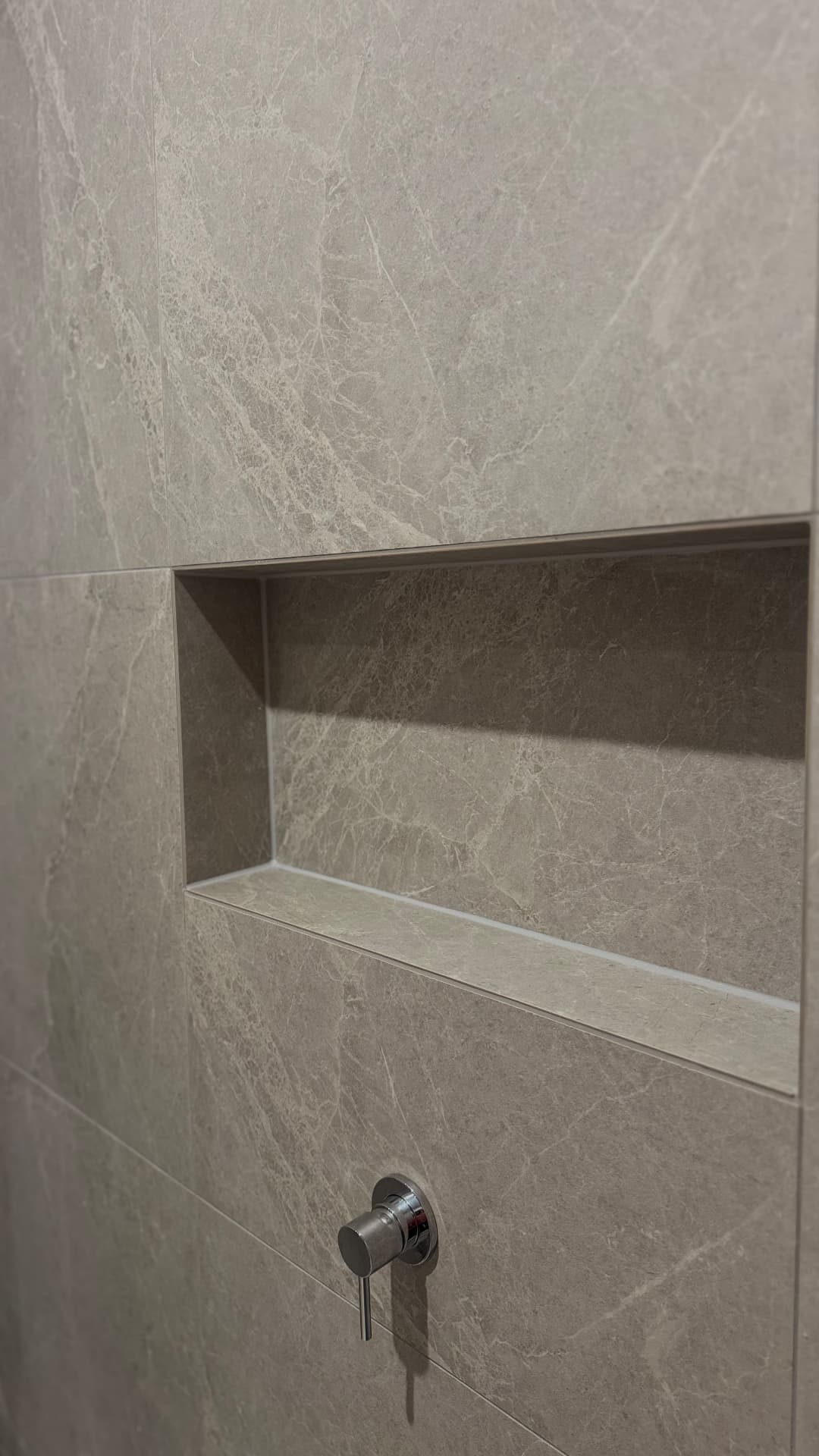 Shower niche with neatly sealed tiled corners and edges