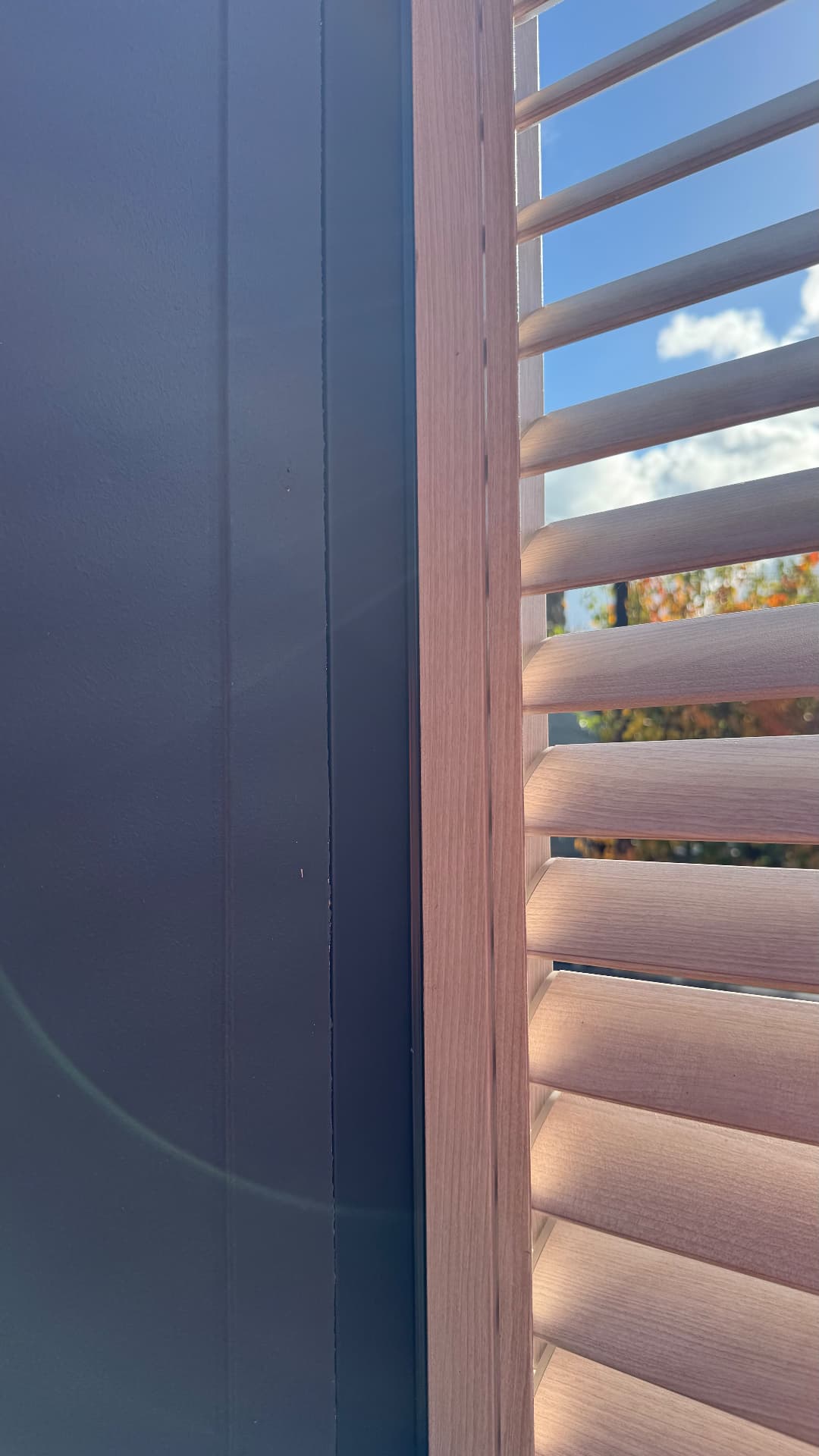 Close-up of sealed junction between timber louvre frame and dark cladding