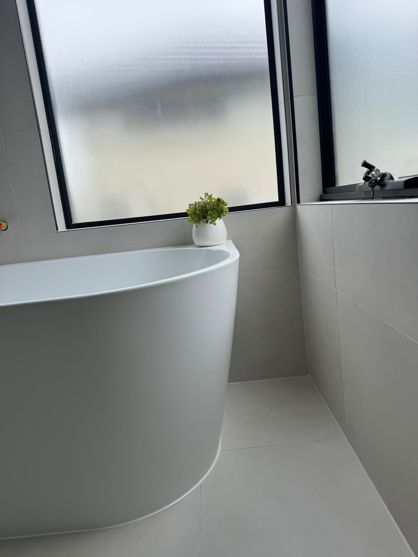 Freestanding bath sealed to tiled walls and floor