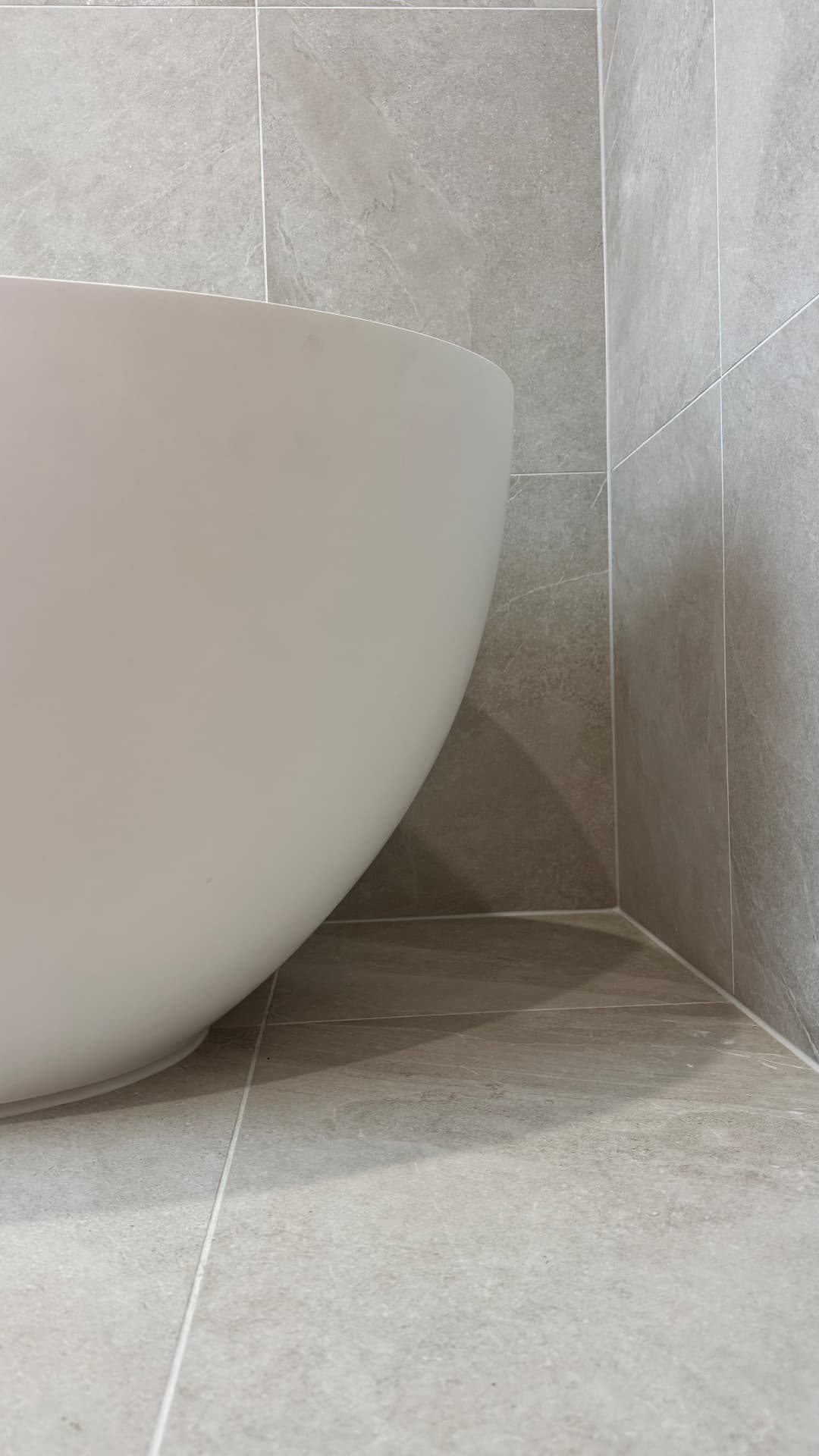 Freestanding bath sealed neatly against tiled walls and floor