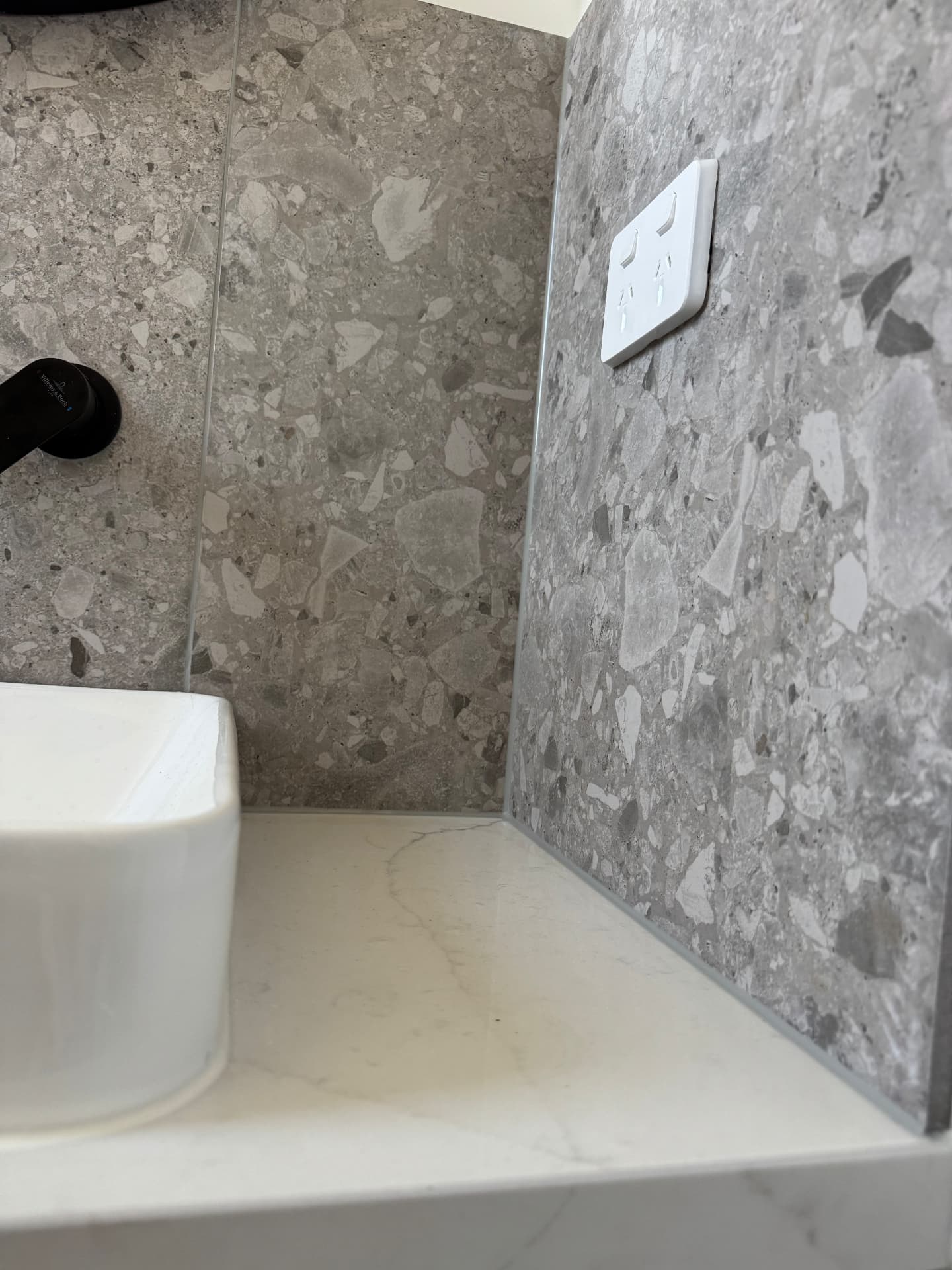 Powder room basin sealed to stone benchtop and terrazzo splashback