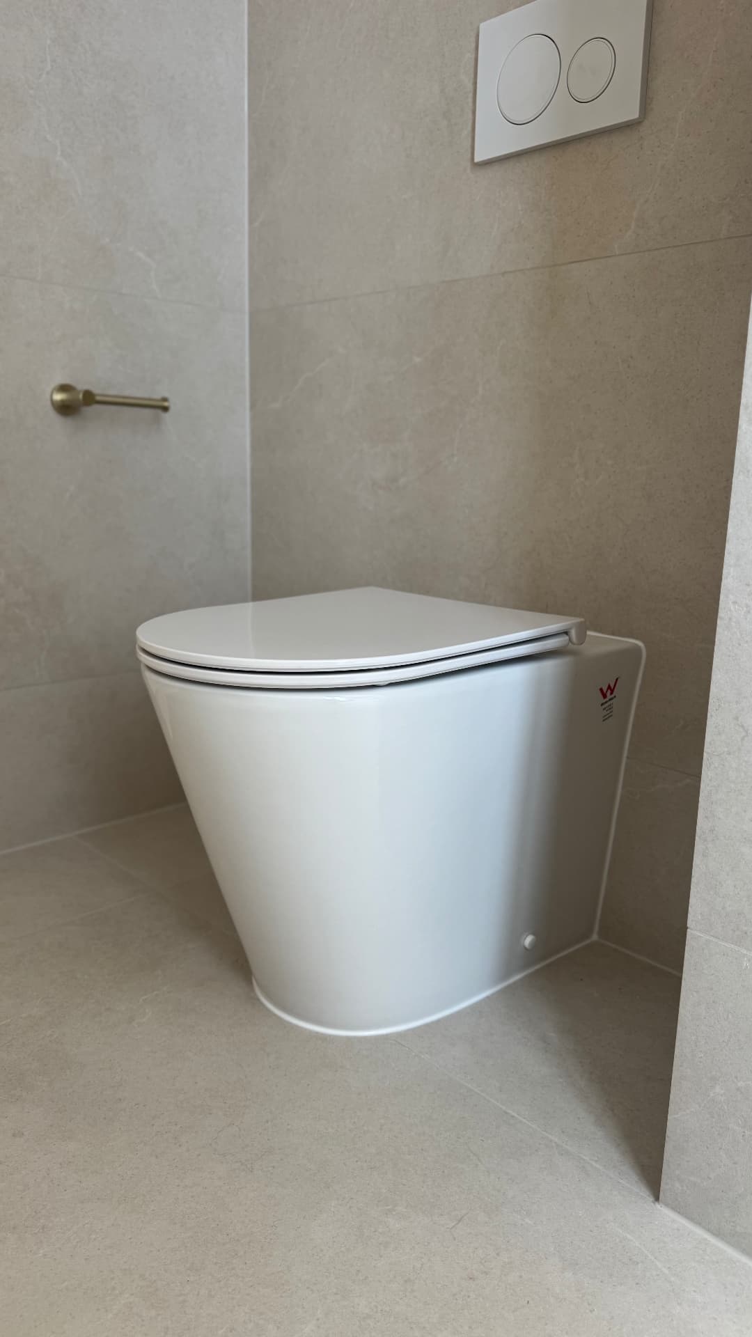 Wall-faced toilet sealed to large-format tiled floor