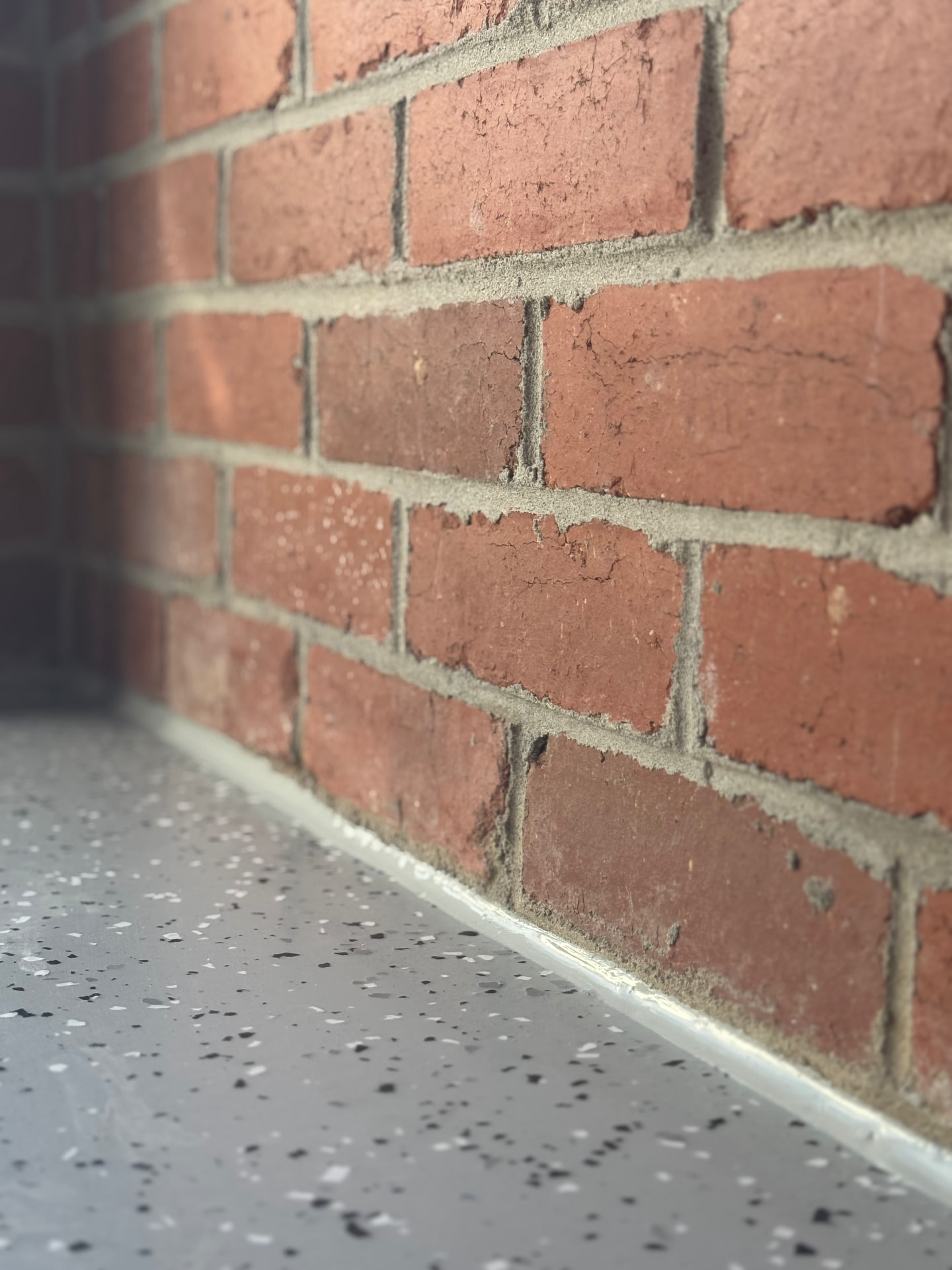 Brick wall sealed to speckled epoxy garage floor