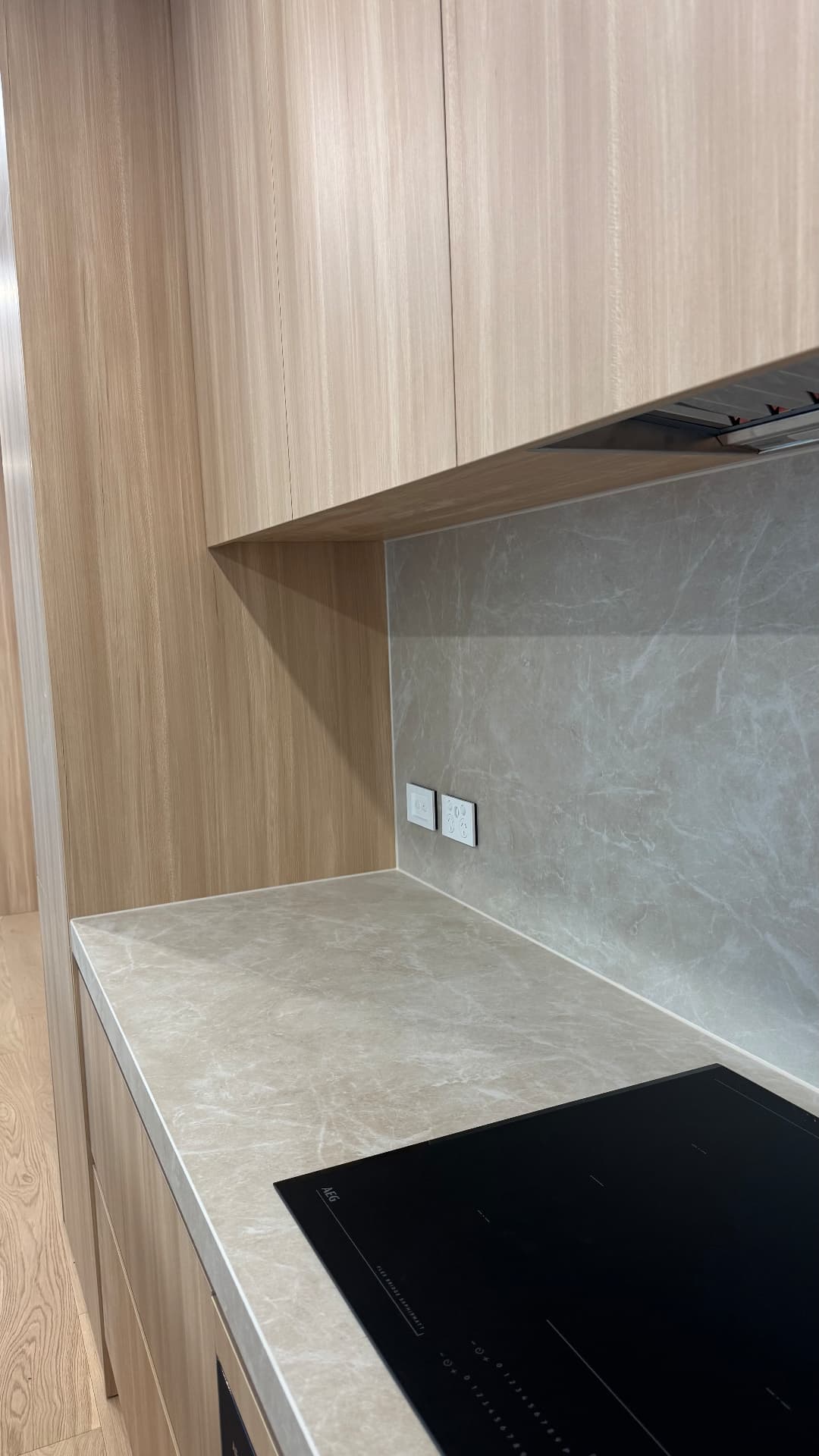 Kitchen cooktop area with sealed stone splashback and benchtop