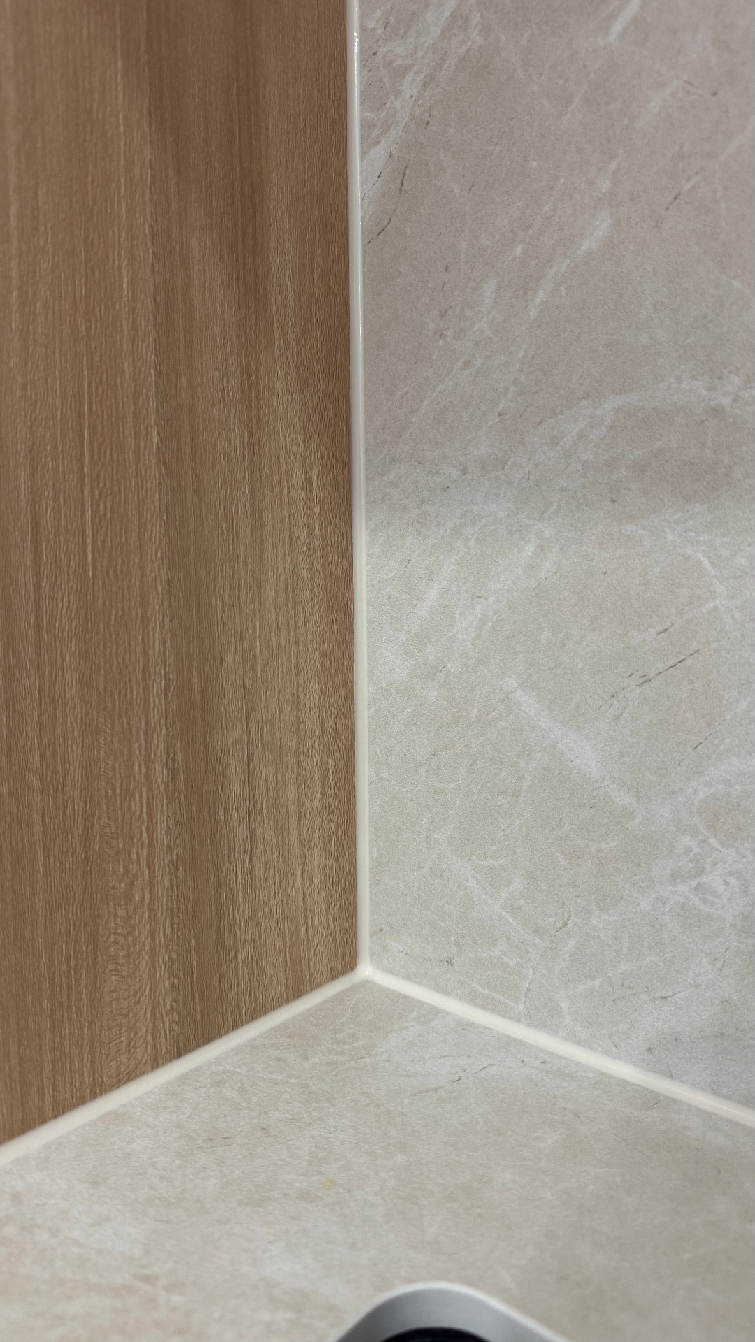 Junta de silicona blanca perfectamente aplicada entre pared alicatada y panel de madera