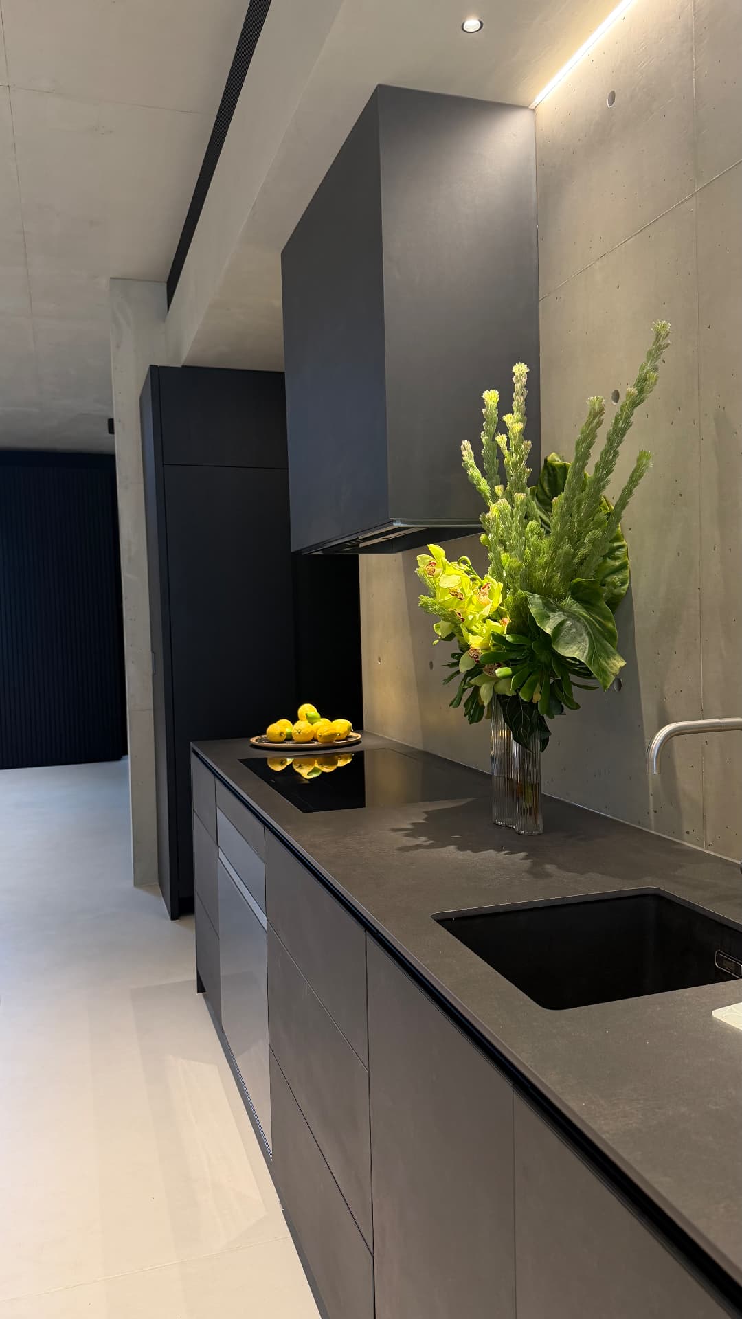 Dark kitchen with sealed stone benchtop, cooktop and splashback joints