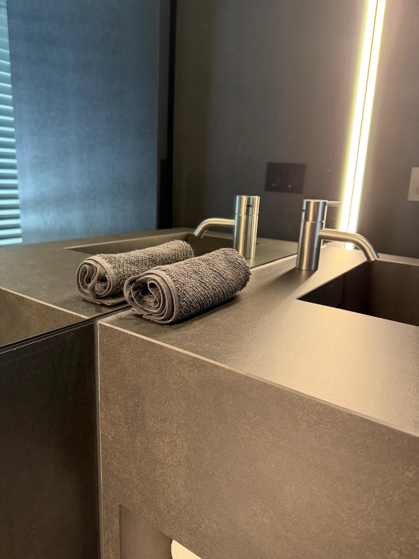 Sealed joints on a dark stone vanity with mirror splashback