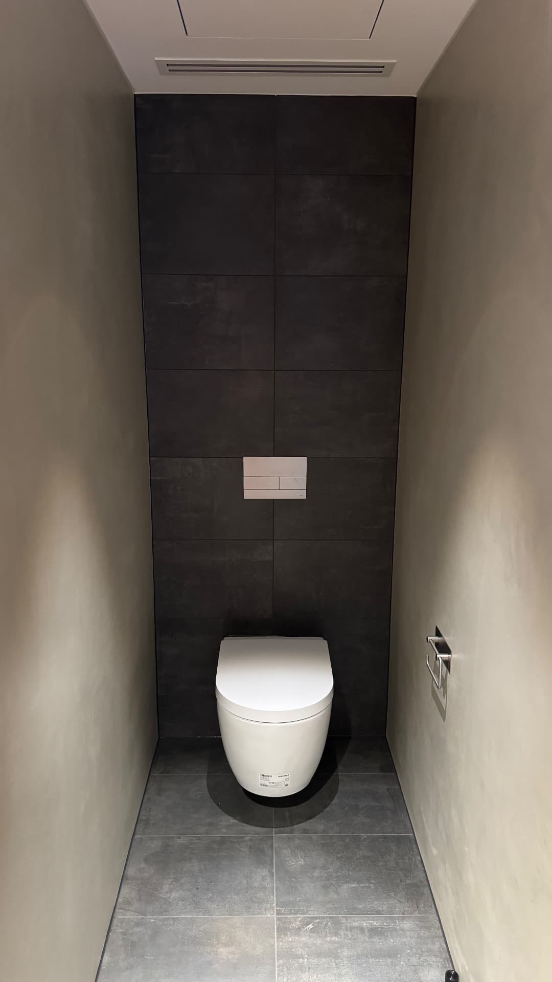 Powder room with sealed wall-hung toilet and tiled feature wall